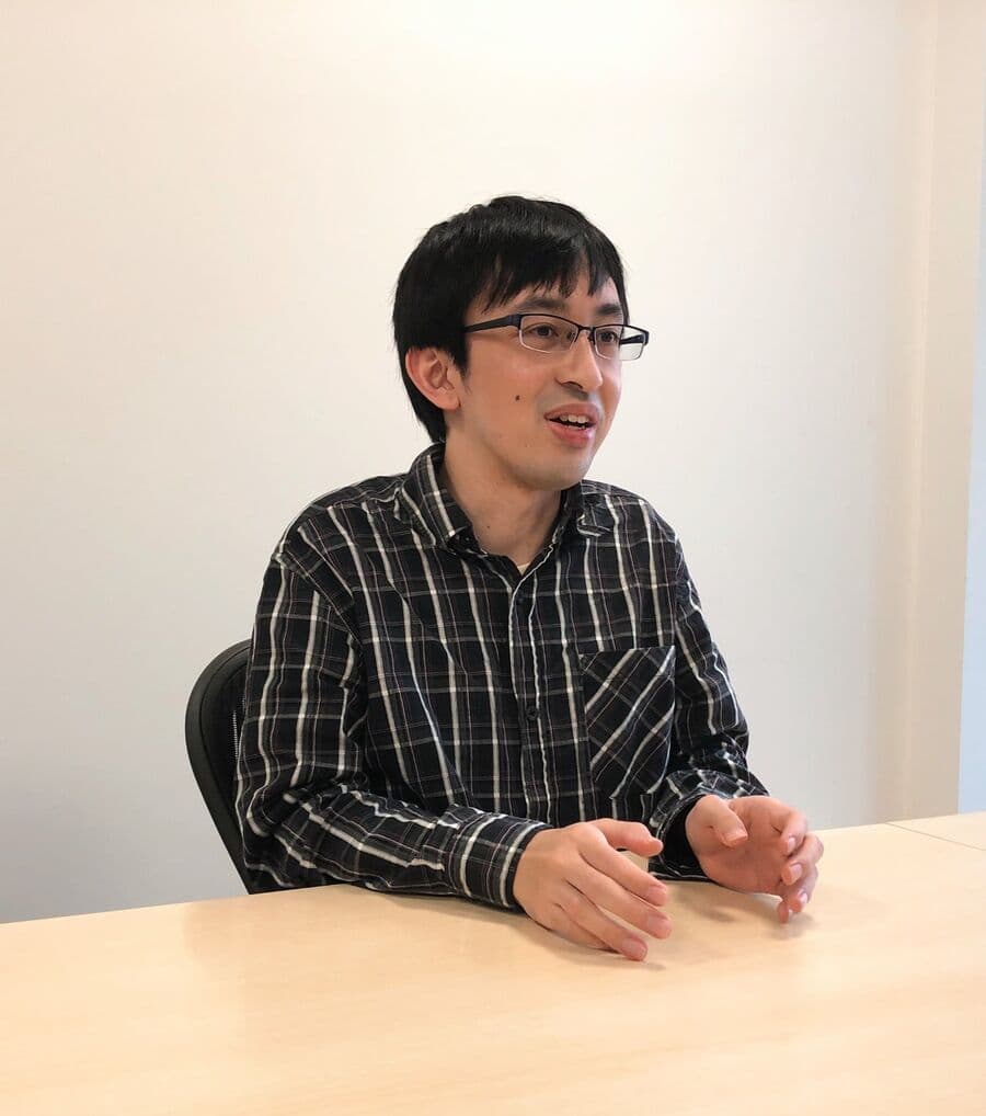 会議室のテーブルで手を動かしながら話すR&D部の機械学習エンジニア